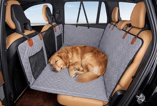 Car interior with a gray quilted bench cover and pet barrier.